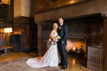Load image into Gallery viewer, Bride and groom in a fireplace portrait at their wedding venue